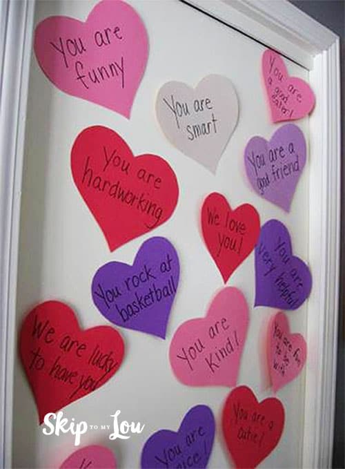 white bedroom door covered with colored cut out hearts with messages on each. A sweet gift for valentine's day on a budget. 