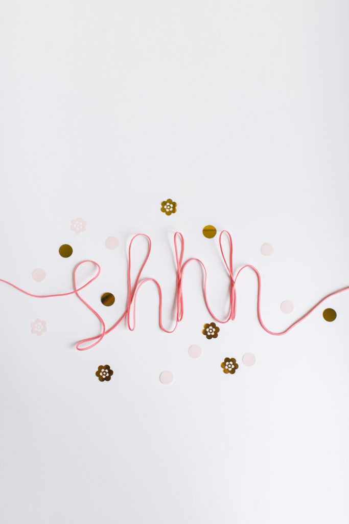 the word shhh written in pink yarn with gold glitter around it